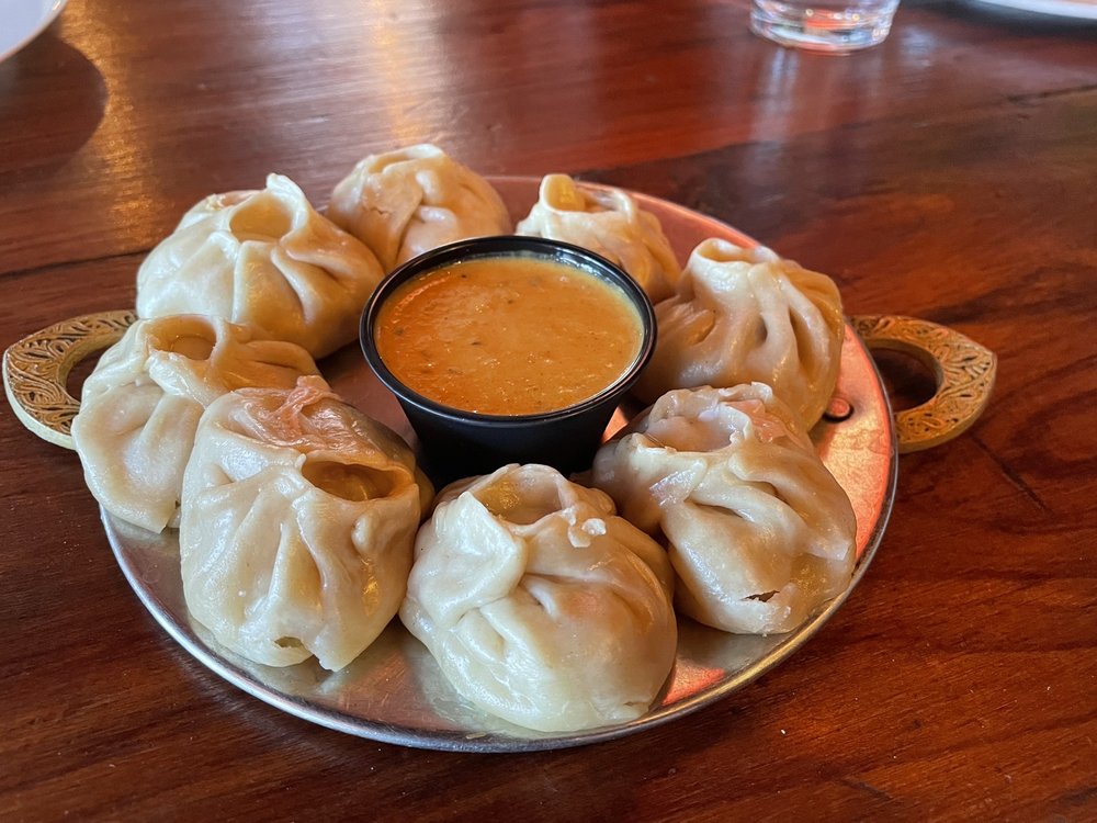 chicken momos on a small plate with dipping sauce